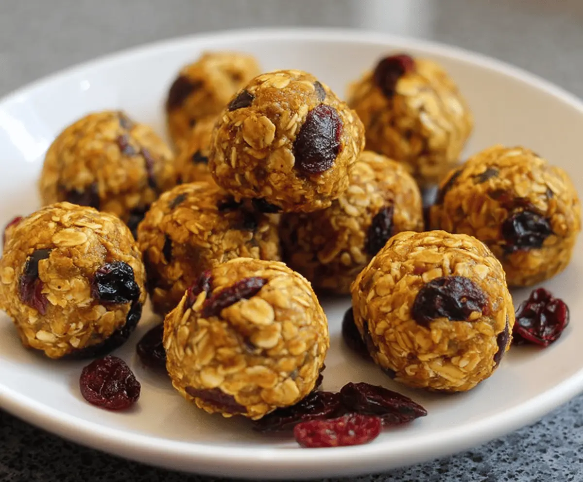 Healthy Pumpkin Cranberry Energy Bites with oats, pumpkin seeds, and dried cranberries on a white plate.
