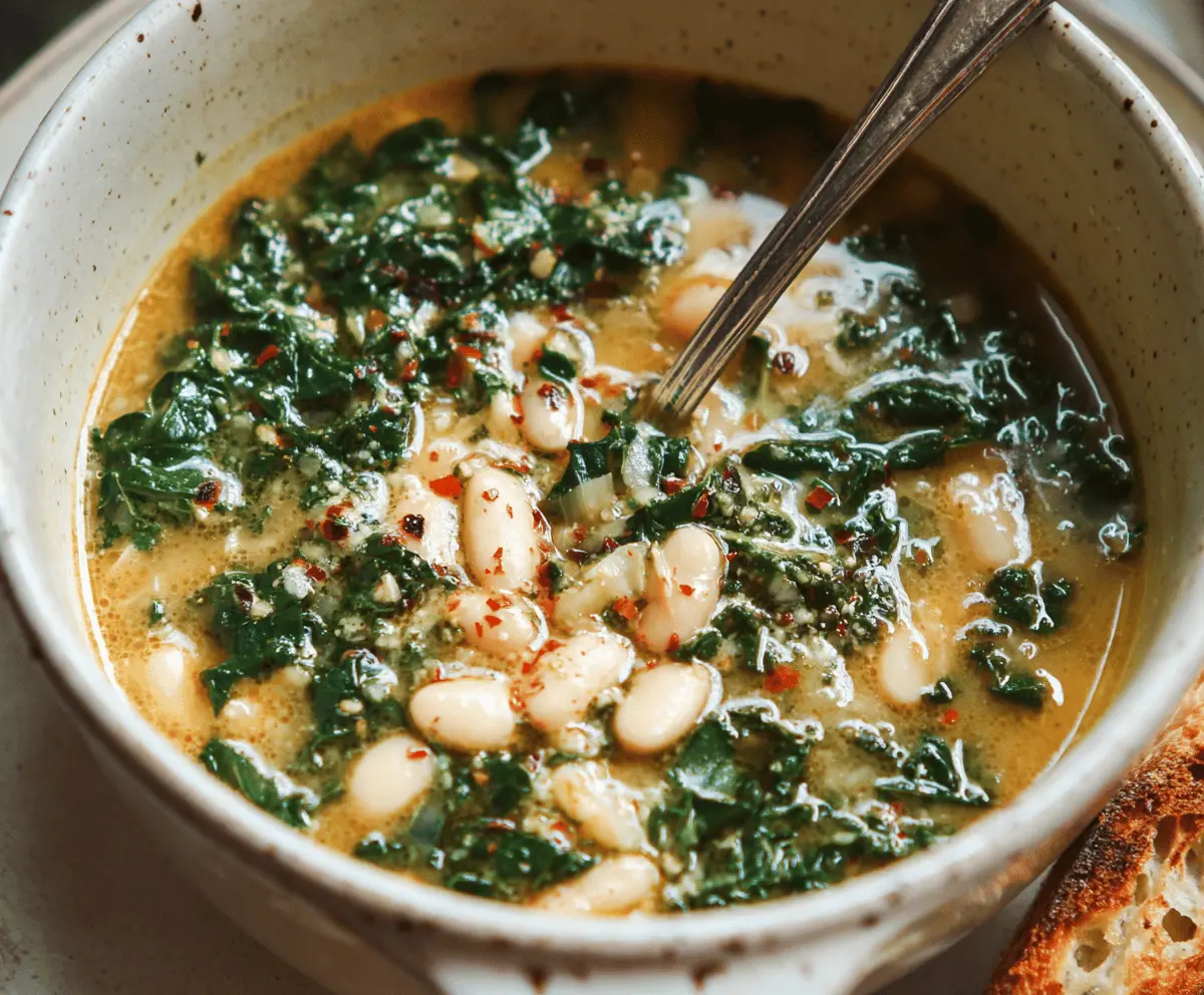 A bowl of hearty White Bean and Kale Soup garnished with fresh herbs, showcasing creamy beans, vibrant green kale, and a comforting broth.