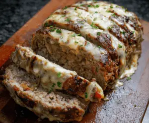 Delicious Philly Cheesesteak Meatloaf topped with melted cheese and sautéed peppers, served on a plate with fresh herbs