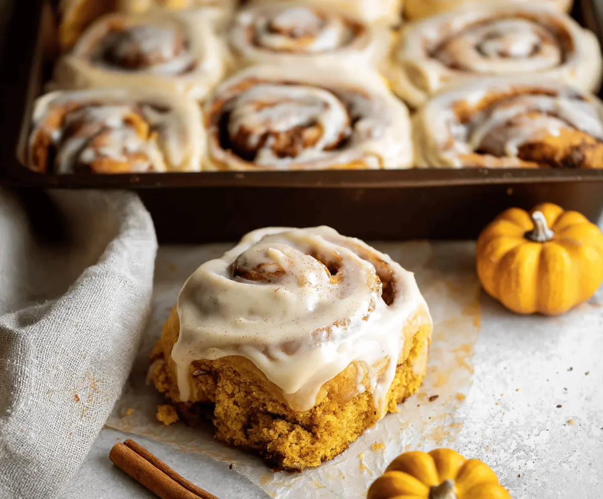 Delicious Pumpkin Cinnamon Rolls topped with Coffee Maple Frosting on a plate, perfect for fall breakfast or dessert