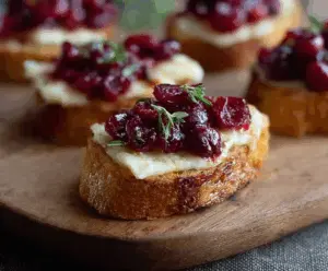 Cranberry Brie Toast topped with fresh cranberries and herbs, served as a festive appetizer