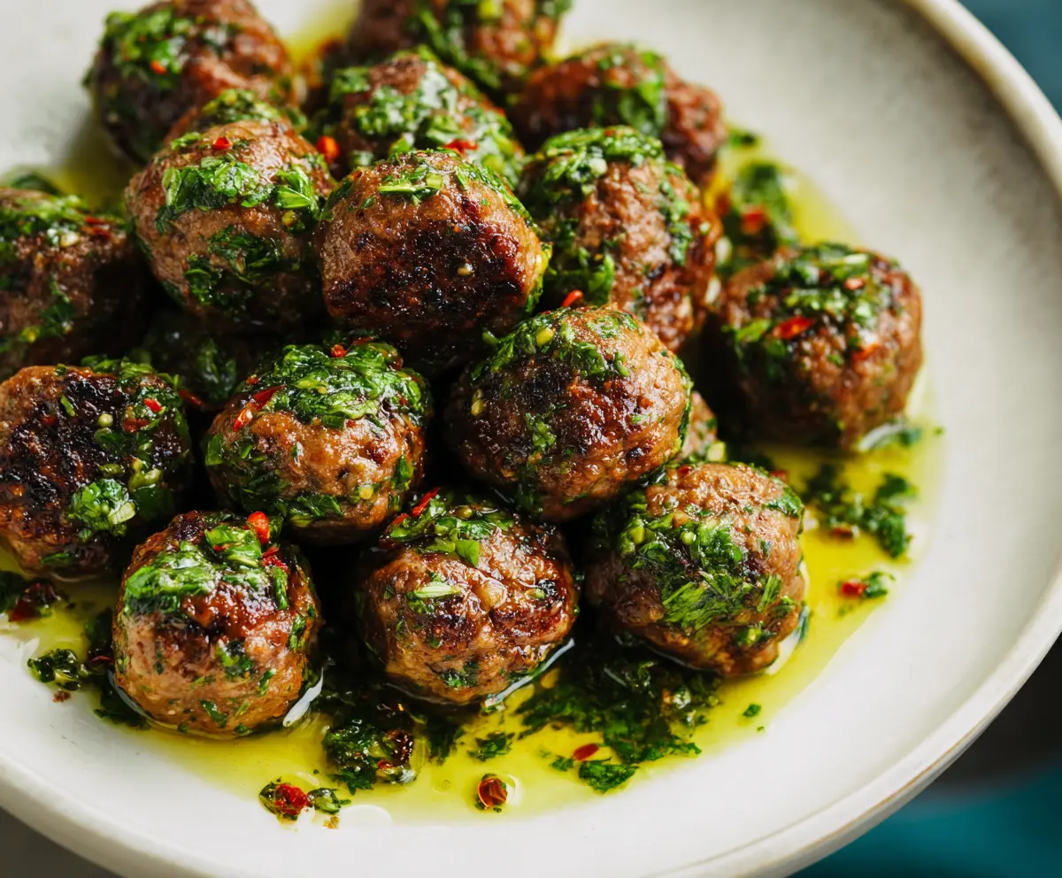 Delicious Chimichurri Meatballs garnished with fresh herbs on a rustic plate.