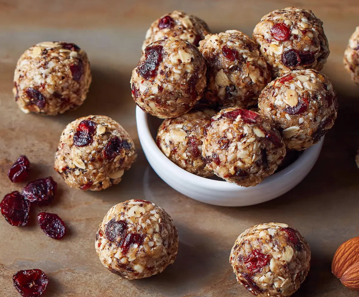 Cranberry Almond Energy Bites on a plate, showing a bite taken out to reveal the chewy, nutty interior.