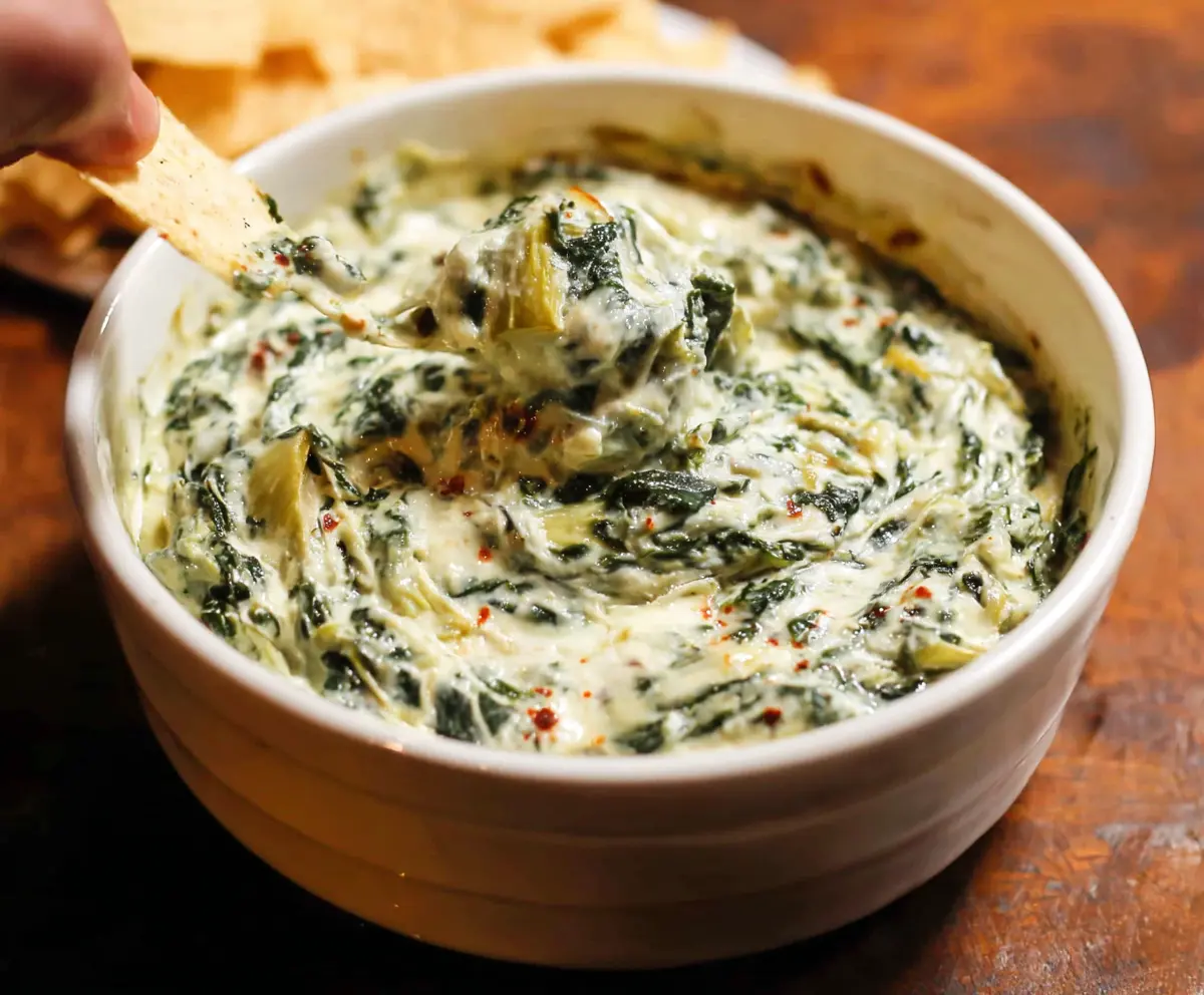 Creamy spinach and artichoke dip served with crispy crackers, perfect for parties and snacks.