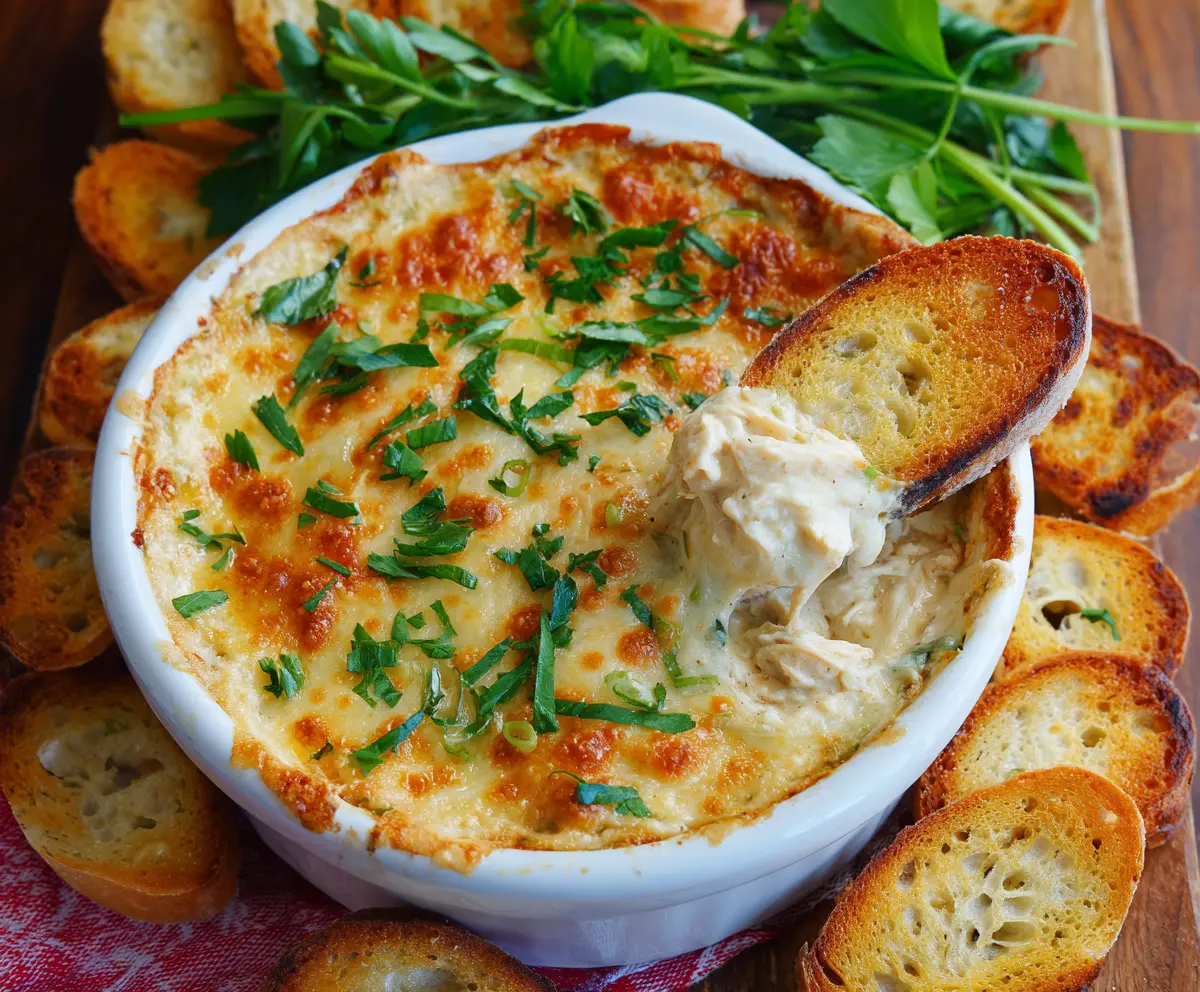 Creamy Baked Chicken Alfredo Dip served hot with melted cheese and herbs.