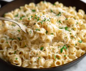 Creamy butter parmesan pasta garnished with fresh herbs in a rustic bowl