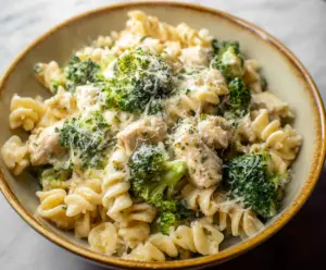 Creamy chicken and broccoli pasta dish served in a bowl, highlighting fresh ingredients and cheesy topping