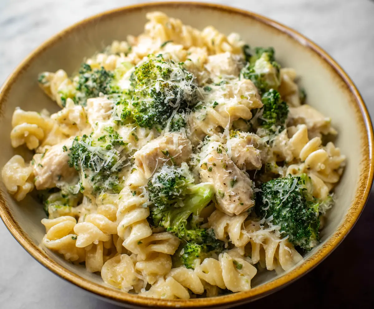 Creamy chicken and broccoli pasta dish served in a bowl, highlighting fresh ingredients and cheesy topping
