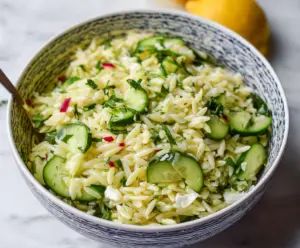 Fresh cucumber and lemon orzo salad served in a bowl, ideal for a light summer meal.