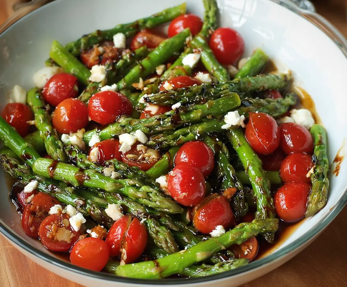 Fresh balsamic asparagus and tomato salad served in a bowl with vibrant vegetables.