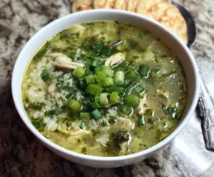 Delicious green garlic and ginger chicken and rice soup served in a bowl with fresh herbs.