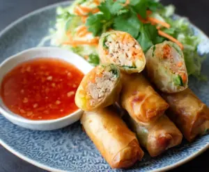 Delicious Thai chicken spring rolls served with sweet chili sauce on a plate, ready to eat.