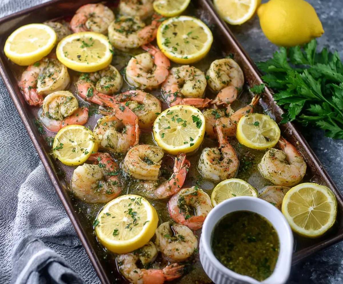 Delicious sheet pan lemon herb shrimp with fresh herbs and lemon slices on a baking sheet.